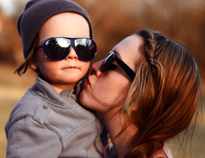 Chelsey kissing toddler Phoenix in sunglasses and a beanie